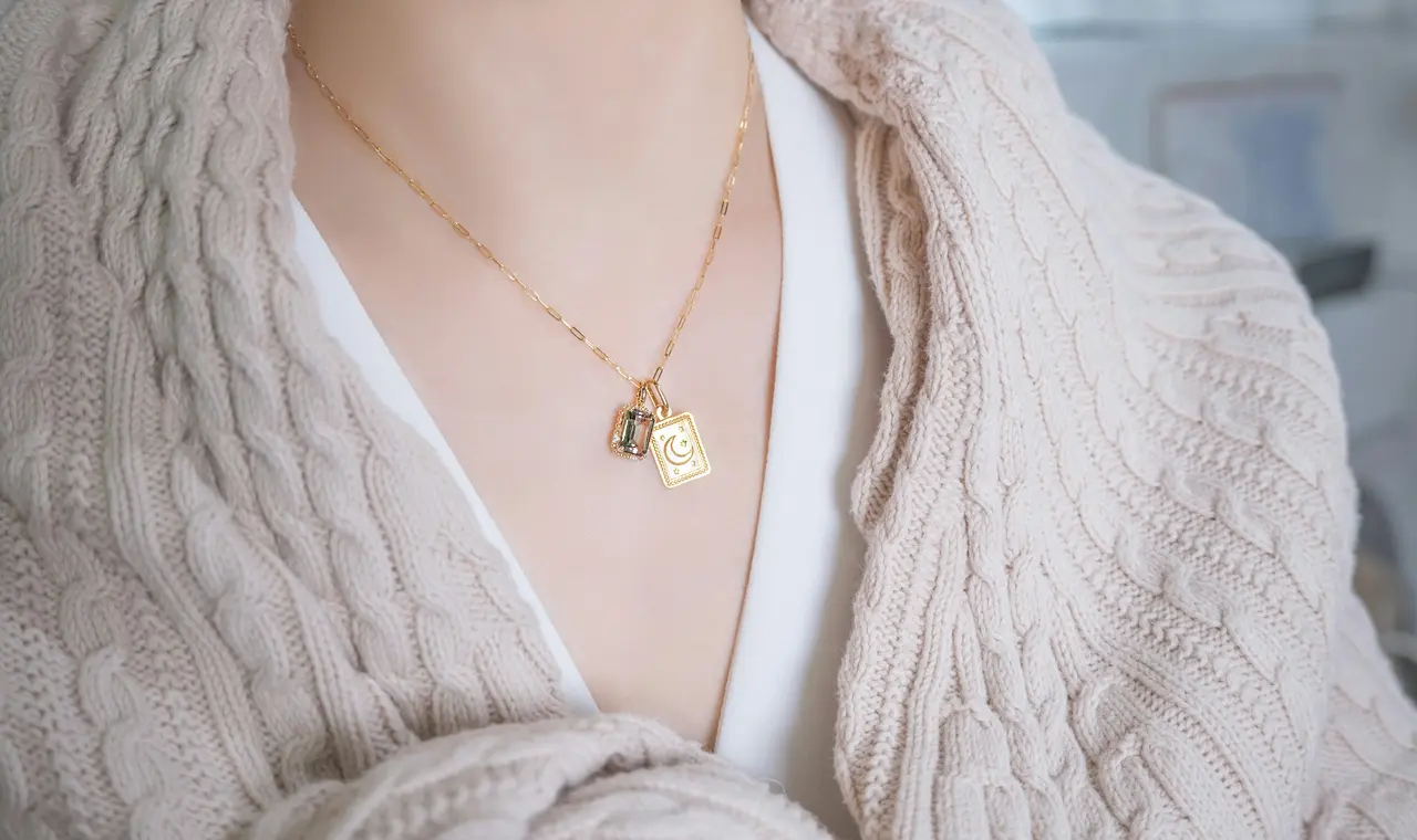 Delikatne złote i srebrne łańcuszki z charmsami ułożone na białym tle